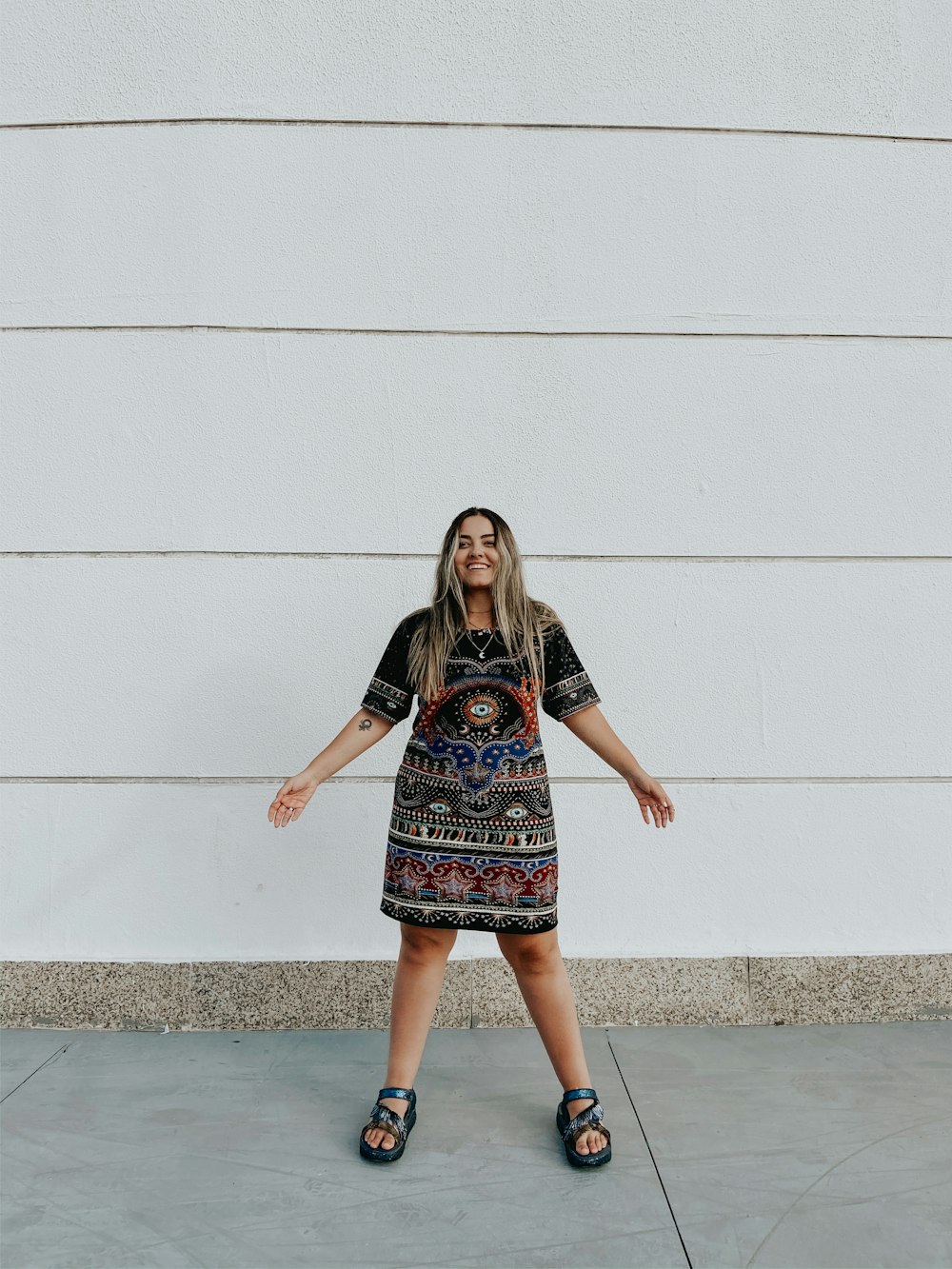 woman in black and red dress standing beside white wall