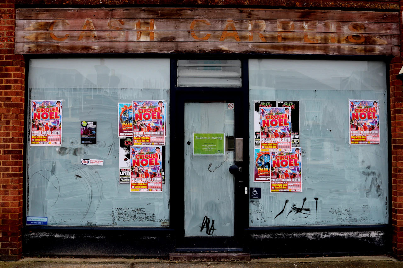 An empty shopfront with posters pasted across its windows