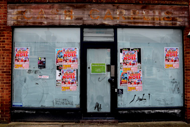 An empty shopfront with posters pasted across its windows
