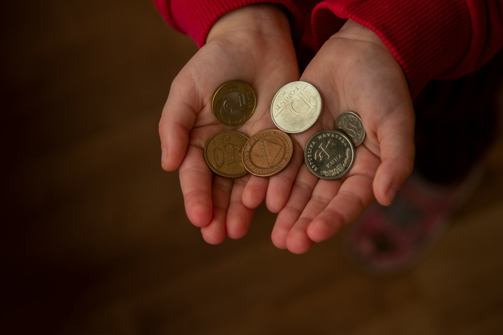 A hand holding several silver coins close-up