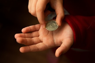 silver round coin on persons hand