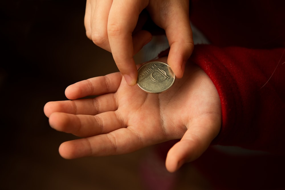 silver round coin on persons hand