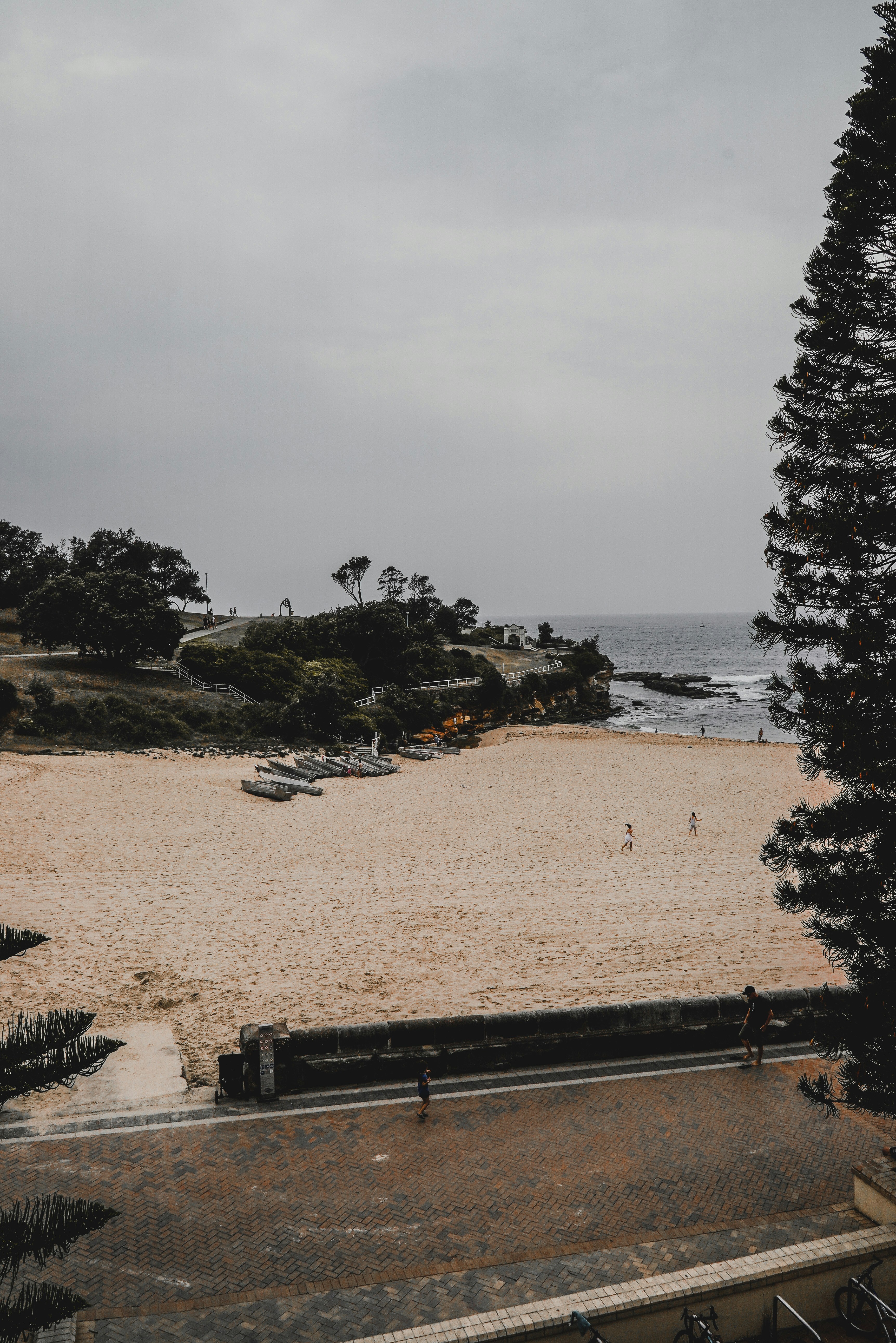 Banco de madera negra sobre arena marrón cerca del cuerpo de agua durante el día