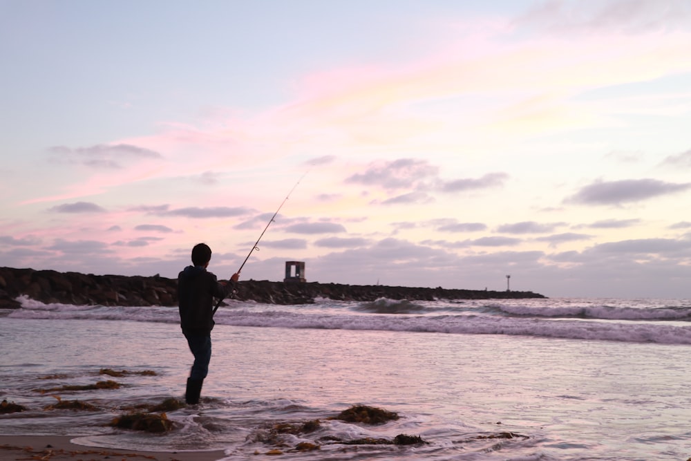 man in black jacket fishing on sea during daytime