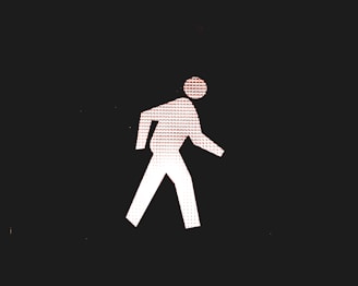 A white stick figure walking symbol is depicted against a black background. The stick figure is composed of a pattern of small repeating characters that resemble the letter R. The figure is shown in mid-step with one leg forward and one arm bent at the elbow.