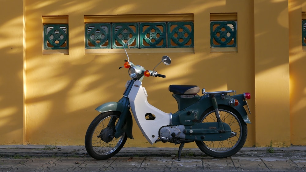 white and black motorcycle parked beside yellow painted wall