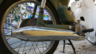 Close-up of a shiny 2-stroke motorcycle exhaust pipe with a sleek design on a vintage bike.