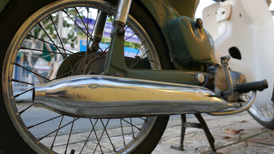 Close-up of a shiny 2-stroke motorcycle exhaust pipe with a sleek design on a vintage bike.