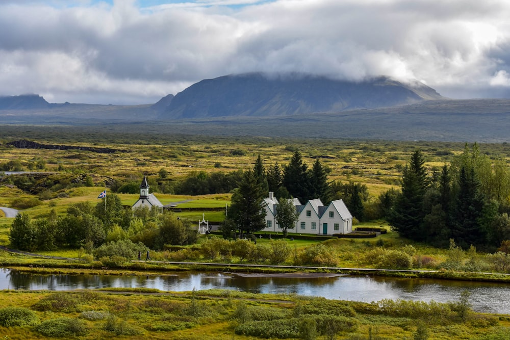 white and brown house near green mountain under white clouds during daytime