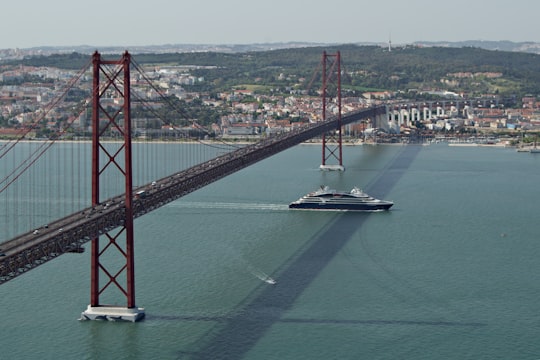 red bridge over body of water during daytime in 25 de Abril Bridge Portugal