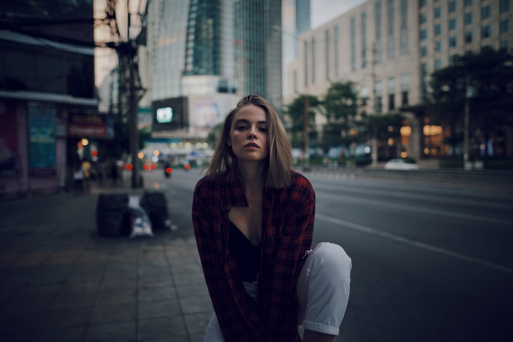 woman in white long sleeve shirt and maroon scarf standing on sidewalk during daytime