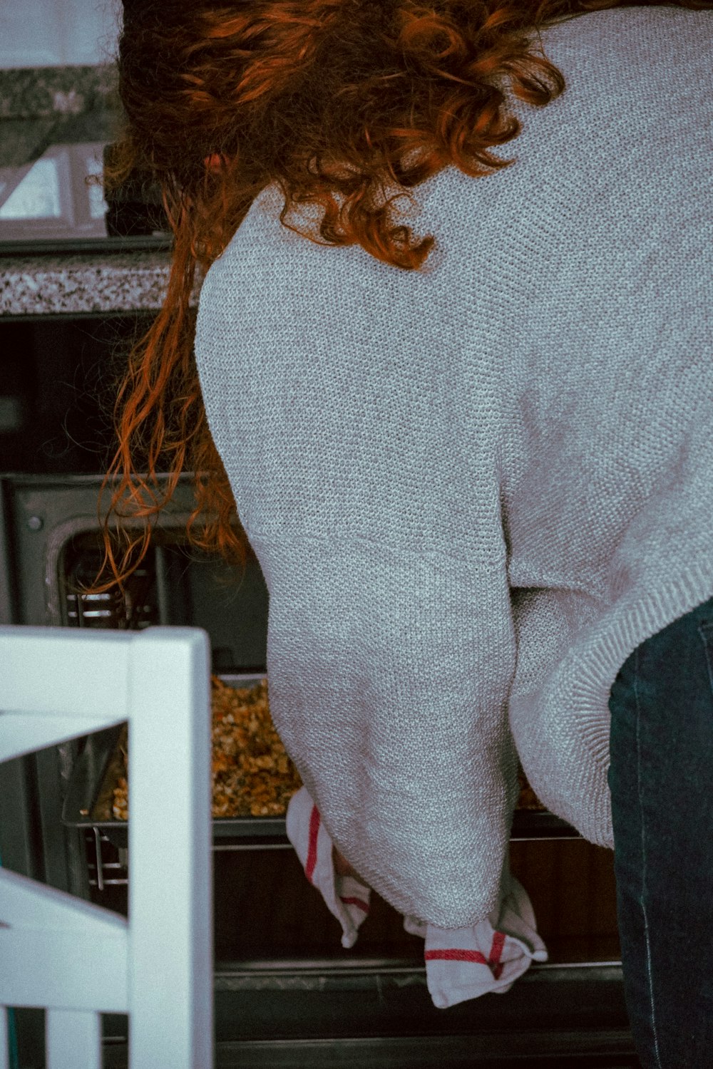 woman in gray sweater standing near white wooden table