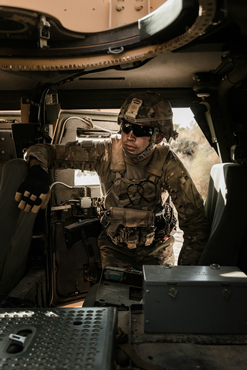 man in brown and black camouflage uniform sitting on black car seat during daytime