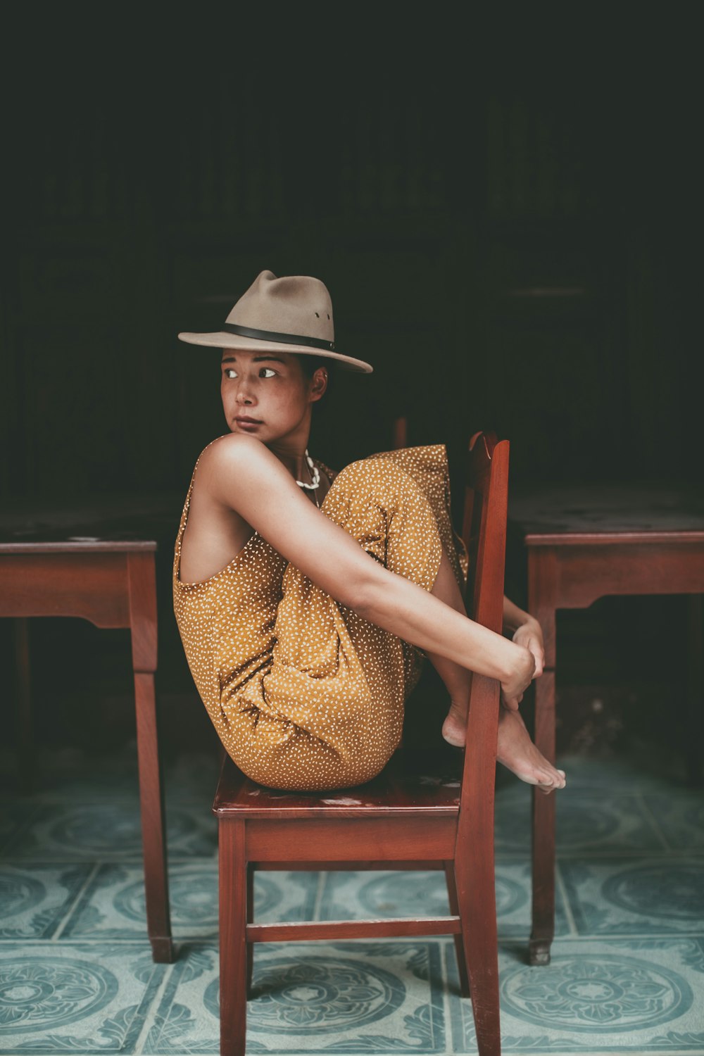Femme en robe jaune sans manches assise sur une chaise en bois marron