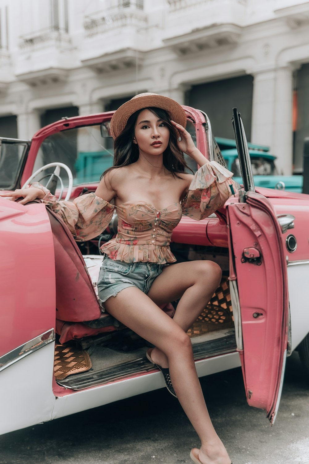 woman in white and red floral spaghetti strap dress sitting on red car