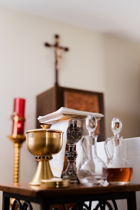 A collection of burgundy religious items displayed on a rustic wooden table with soft natural light.