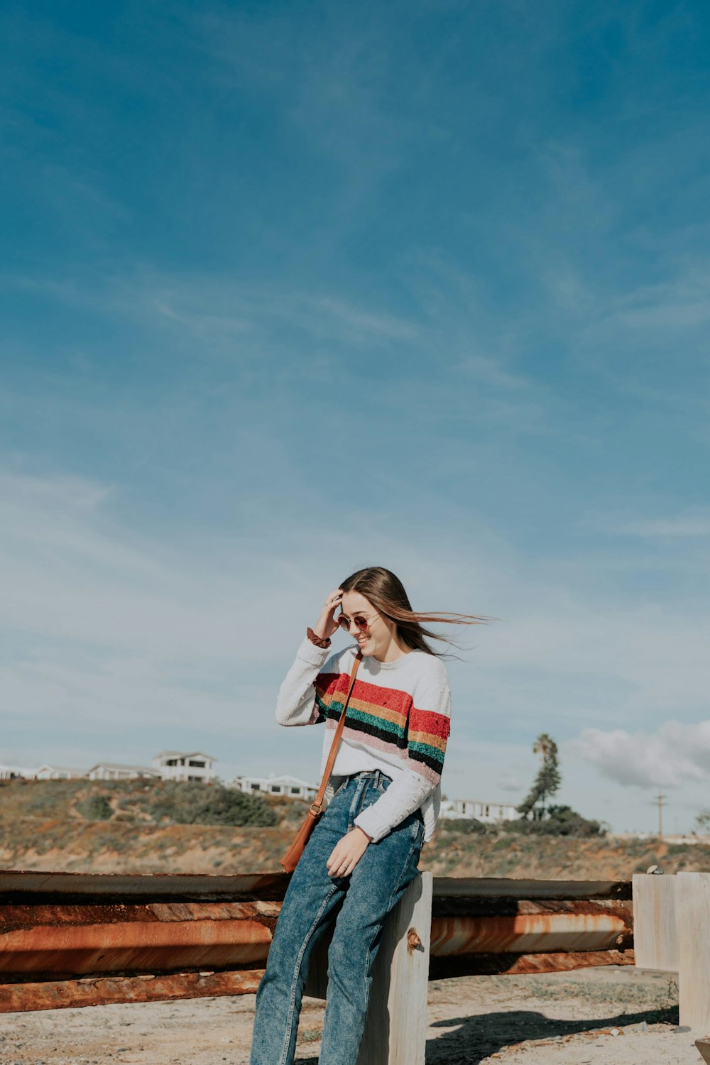 woman in white and red striped long sleeve shirt and blue denim jeans standing on brown
