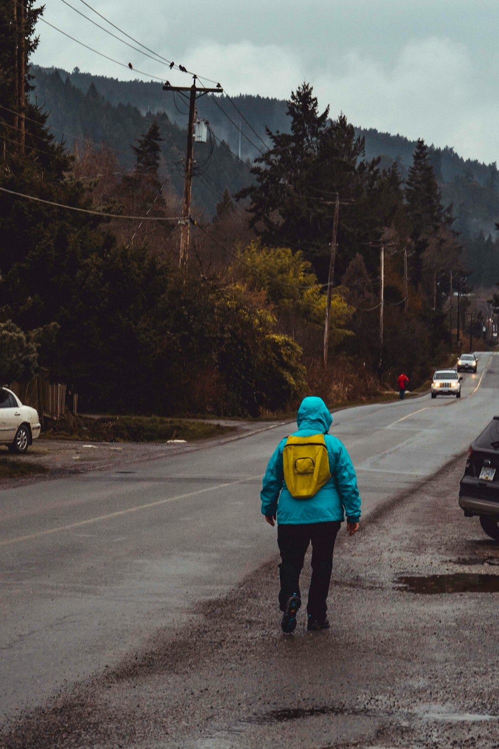 person in green hoodie standing on road during daytime