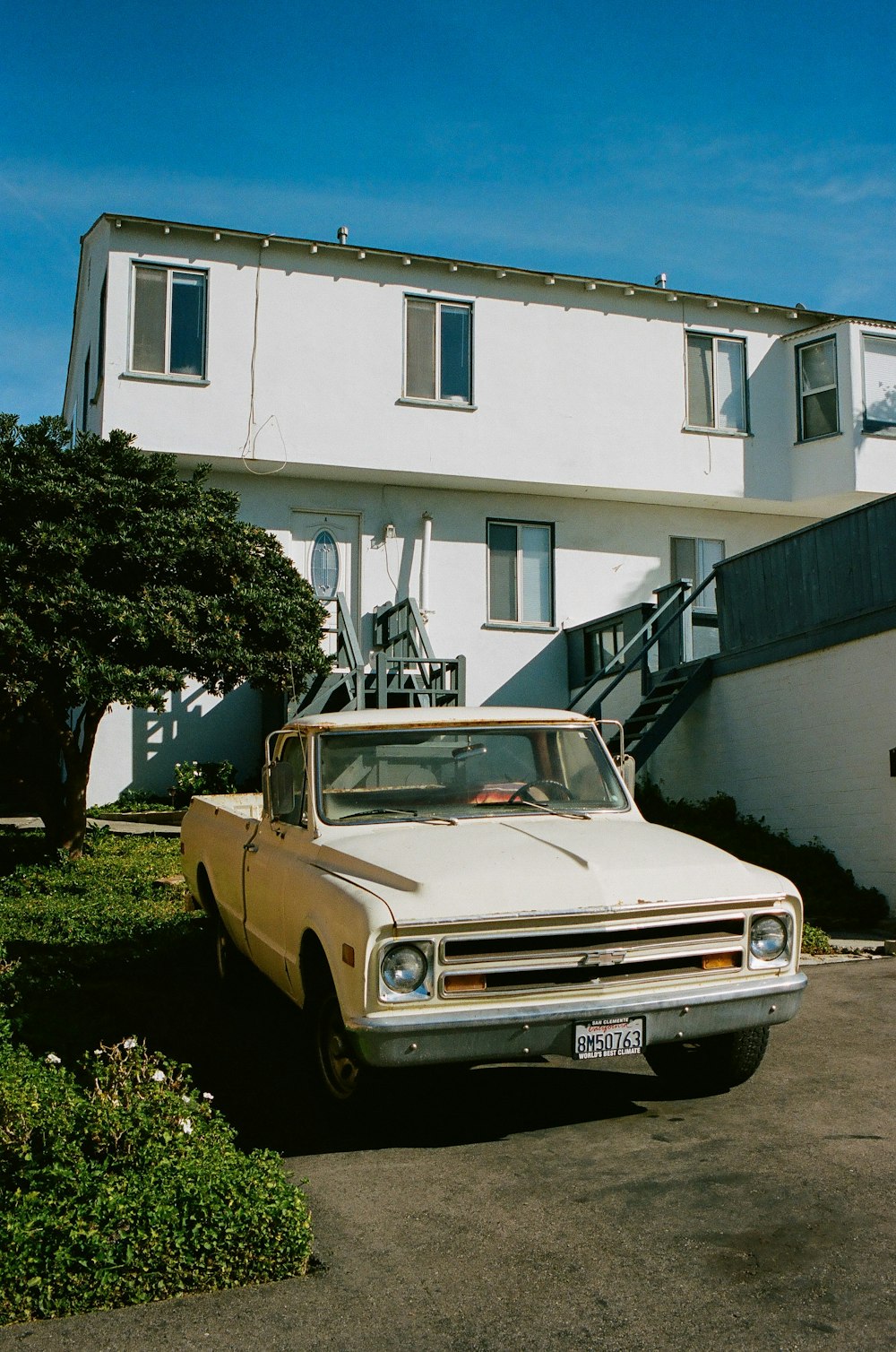 beige car parked beside white concrete building