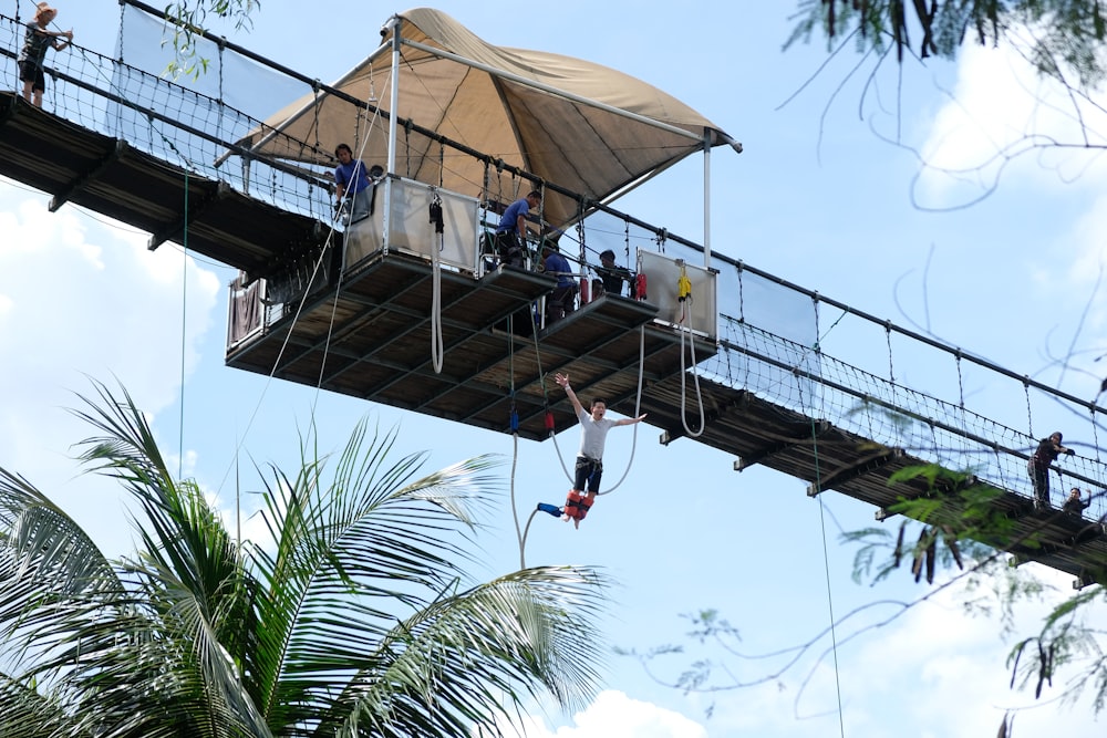 昼間、茶色い木製の吊り橋の上にいる人々
