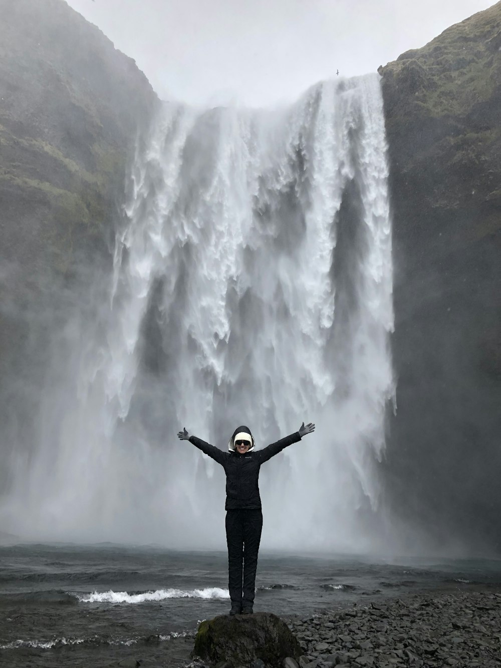 man in black jacket standing near waterfalls