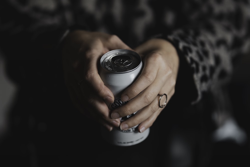 person holding black and silver round container