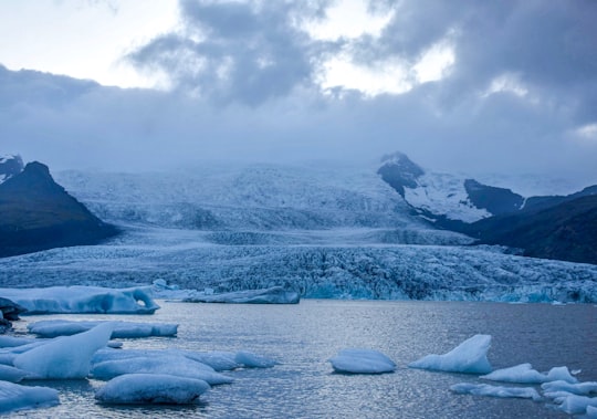 snow covered field near mountain under white clouds during daytime in Vatnajökull National Park Iceland