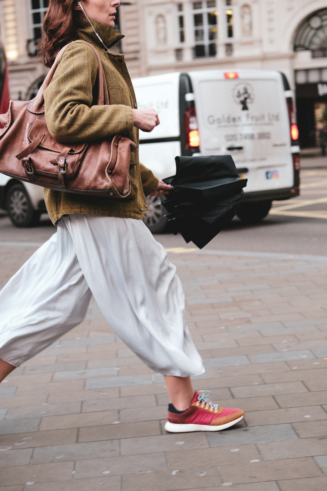 woman in white pants carrying brown leather backpack