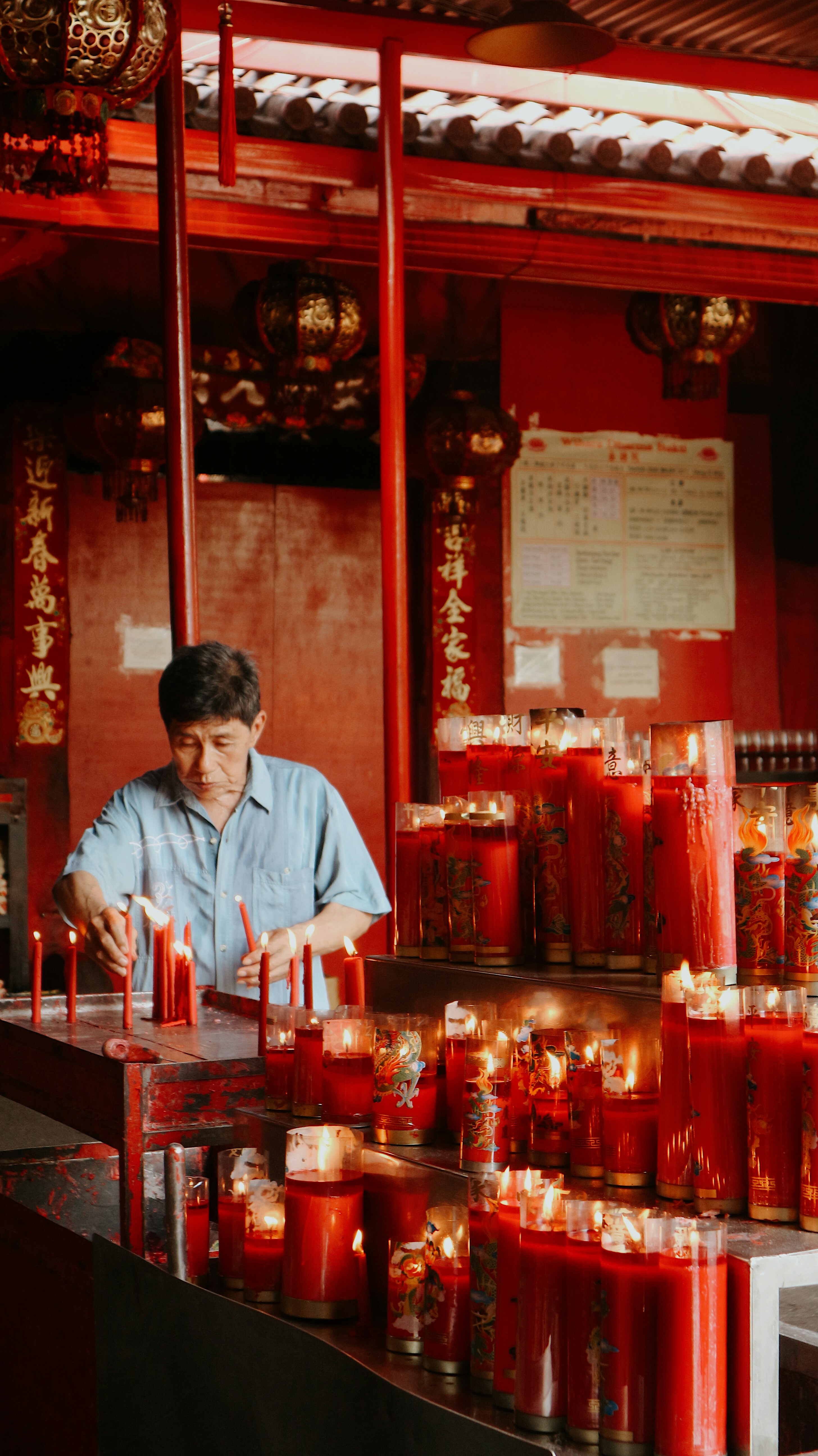 A man in a red room lighting red candles is captured in festive Lunar New Year videos that use royalty free Chinese New Year music.