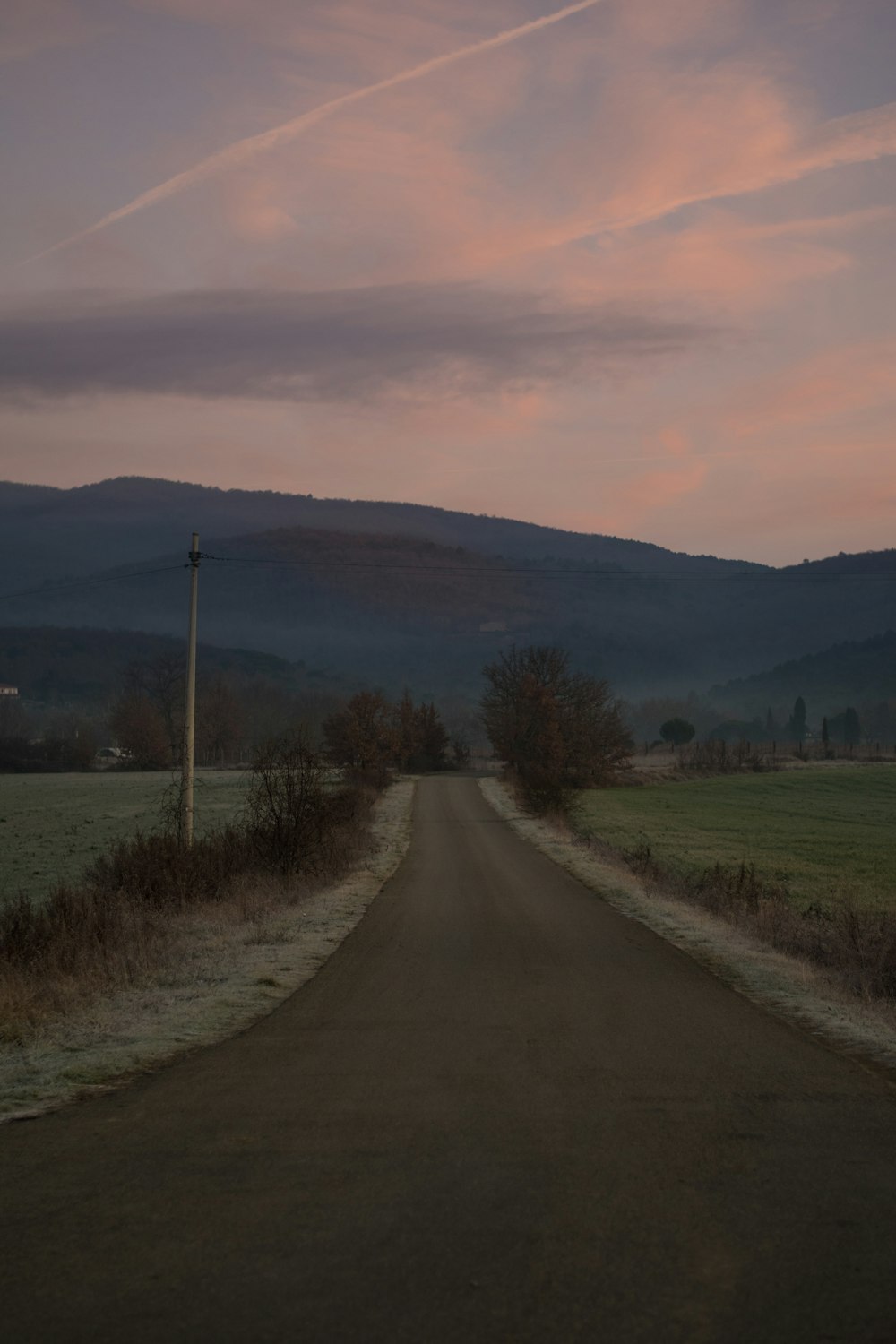 route goudronnée grise entre un champ d’herbe verte pendant la journée