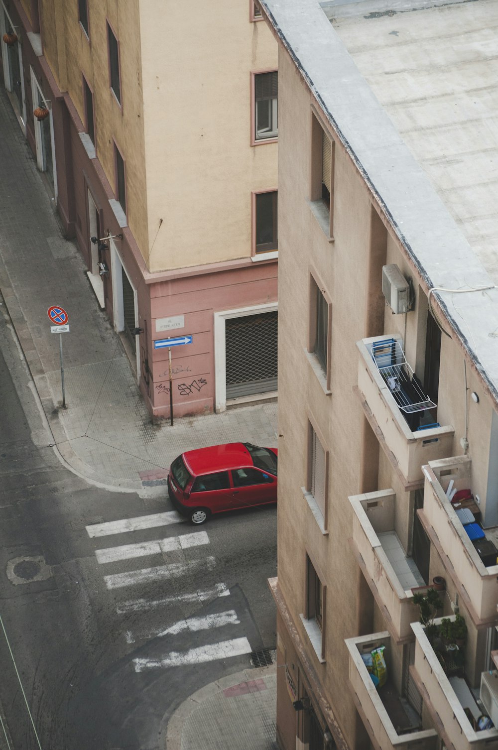 a red car driving down a street next to tall buildings