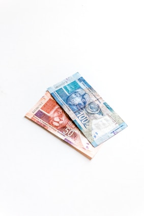 Two banknotes, one valued at 100 and the other at 50, featuring images of animals, are placed on a white surface. The notes are intricately designed with vibrant colors and details.