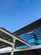 A sleek modern building with glass facades reflecting a clear sky, showcasing architectural precision.