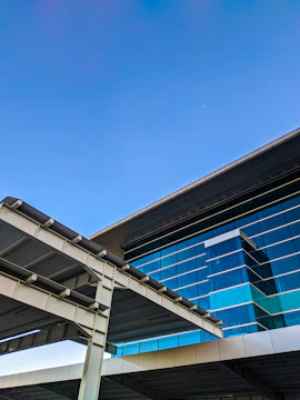 A sleek modern building with glass facades reflecting a clear sky, showcasing architectural precision.