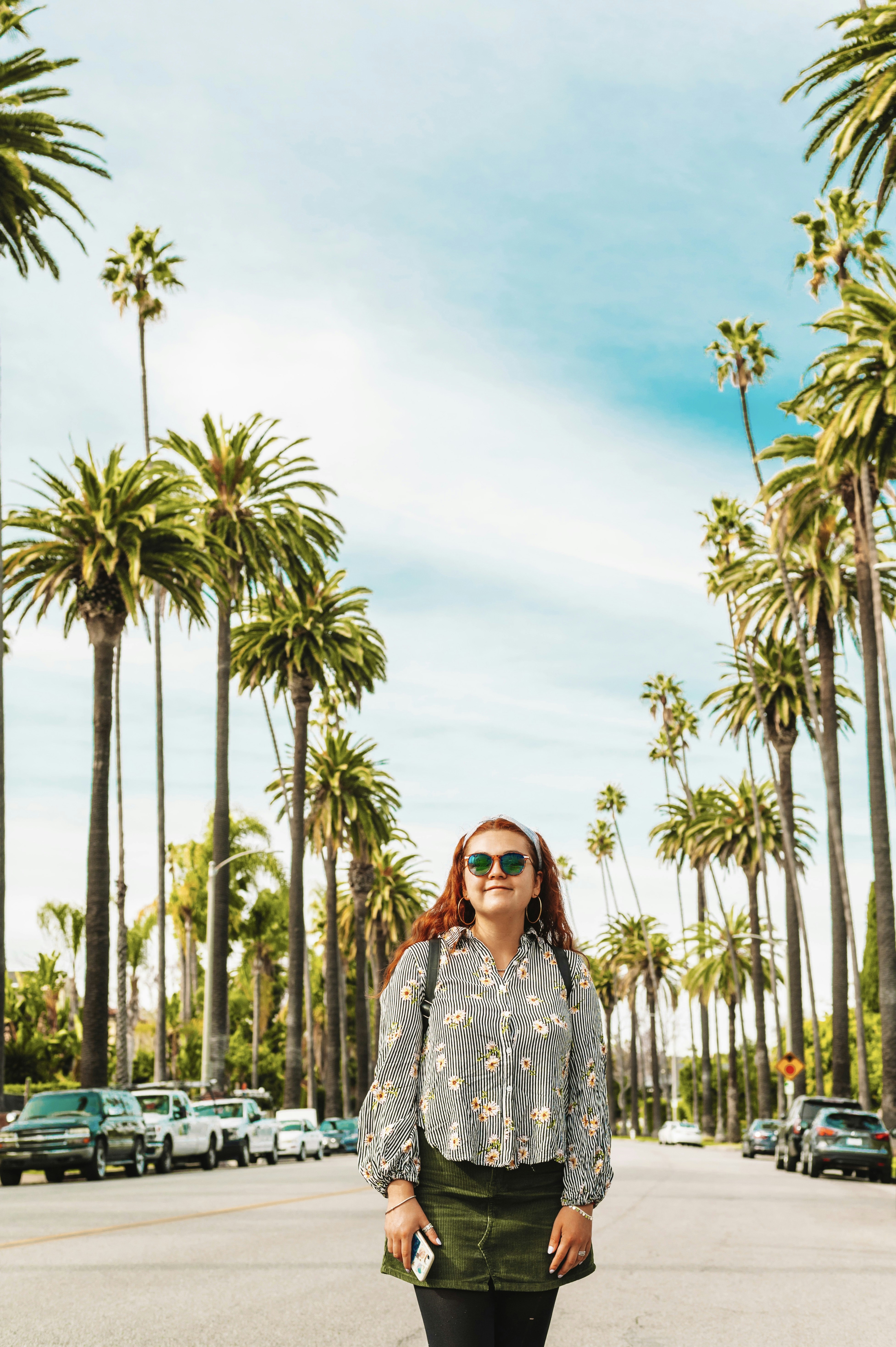 Mujer en vestido floral blanco y negro de pie cerca de las palmeras durante el día