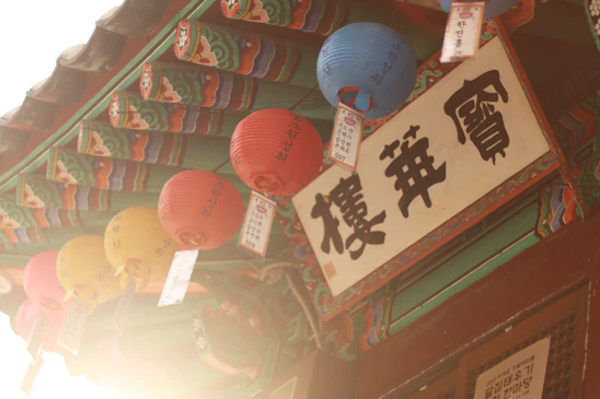 A warm, inviting photo of a cozy Korean street at dusk with soft lantern lights and traditional architecture.