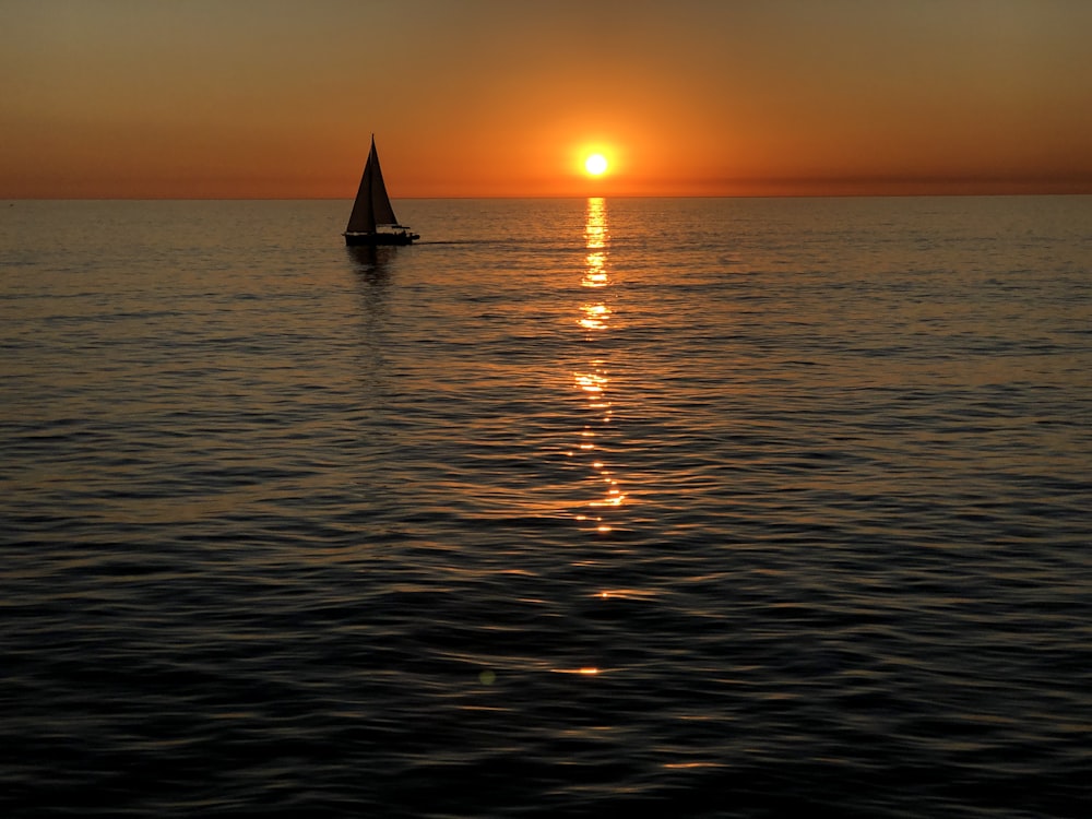 silhouette of sailboat on sea during sunset