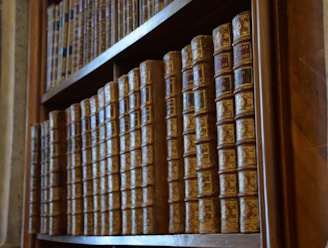 A collection of antique books stacked on a wooden shelf.