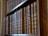 A row of antique, leather-bound books with ornate spines are neatly arranged on a wooden bookshelf.