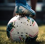 white and blue soccer ball on green grass field