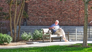 A thoughtful person reading a newspaper on a park bench.