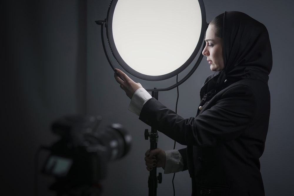 woman in black hoodie holding round mirror