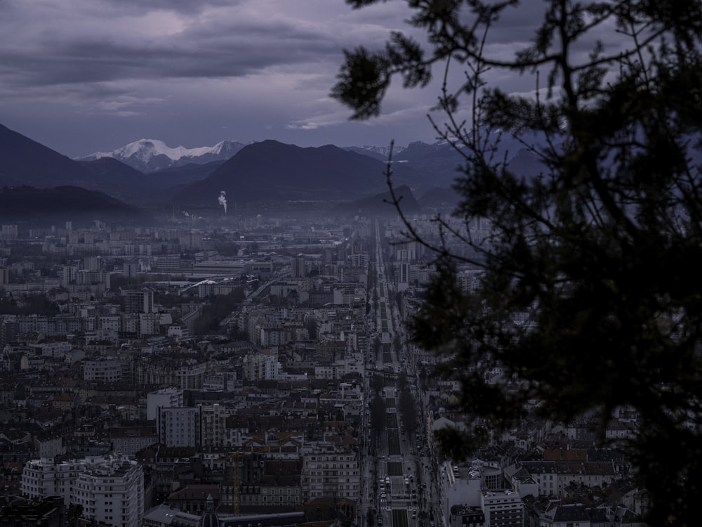 ciudad con edificios de gran altura cerca de la montaña bajo nubes blancas durante el día