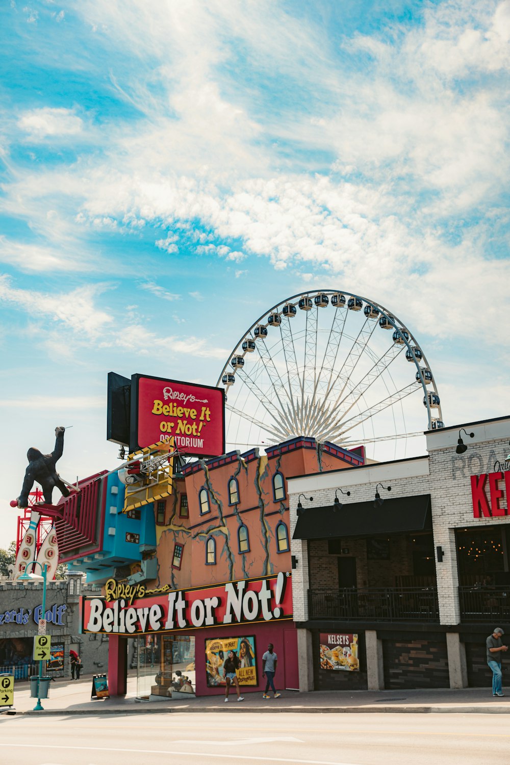 man in red t-shirt and blue denim jeans standing on white and red ferris wheel