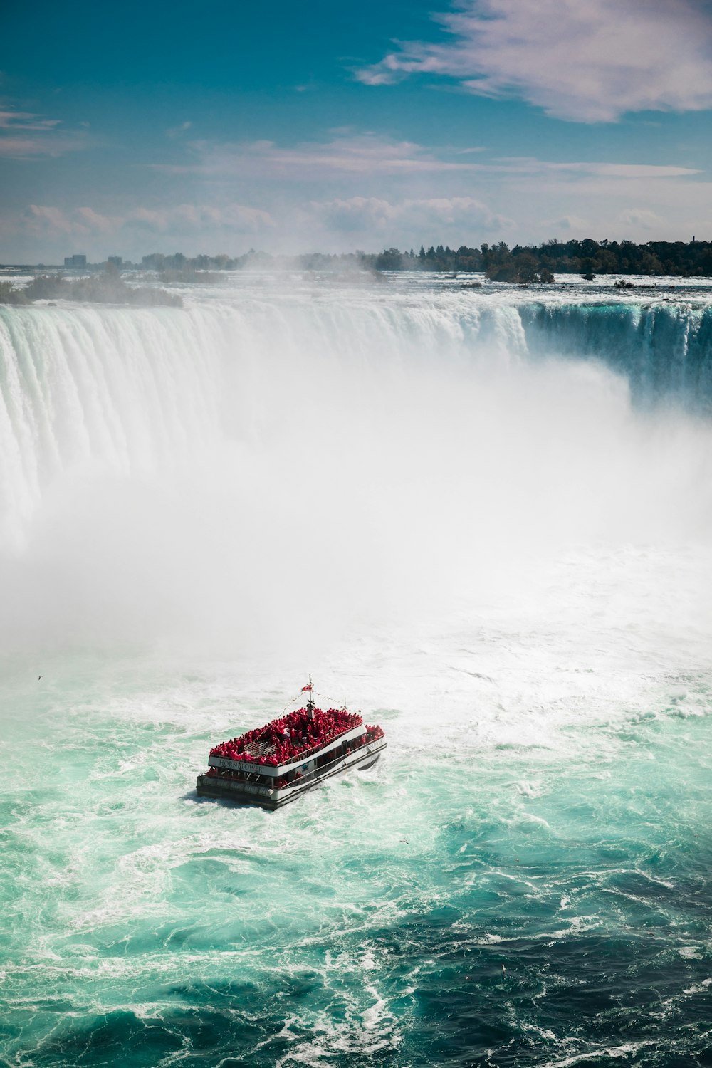 Rotes Boot auf Wasserfällen während des Tages