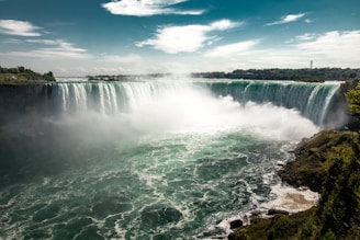 water falls under blue sky during daytime