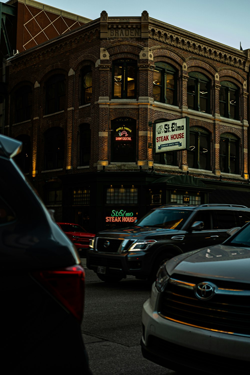 cars parked in front of brown building during night time