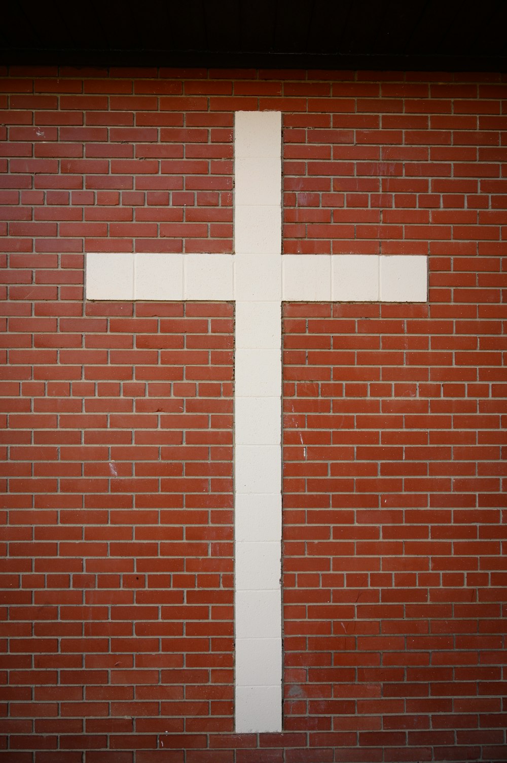 cruz branca na parede marrom do tijolo