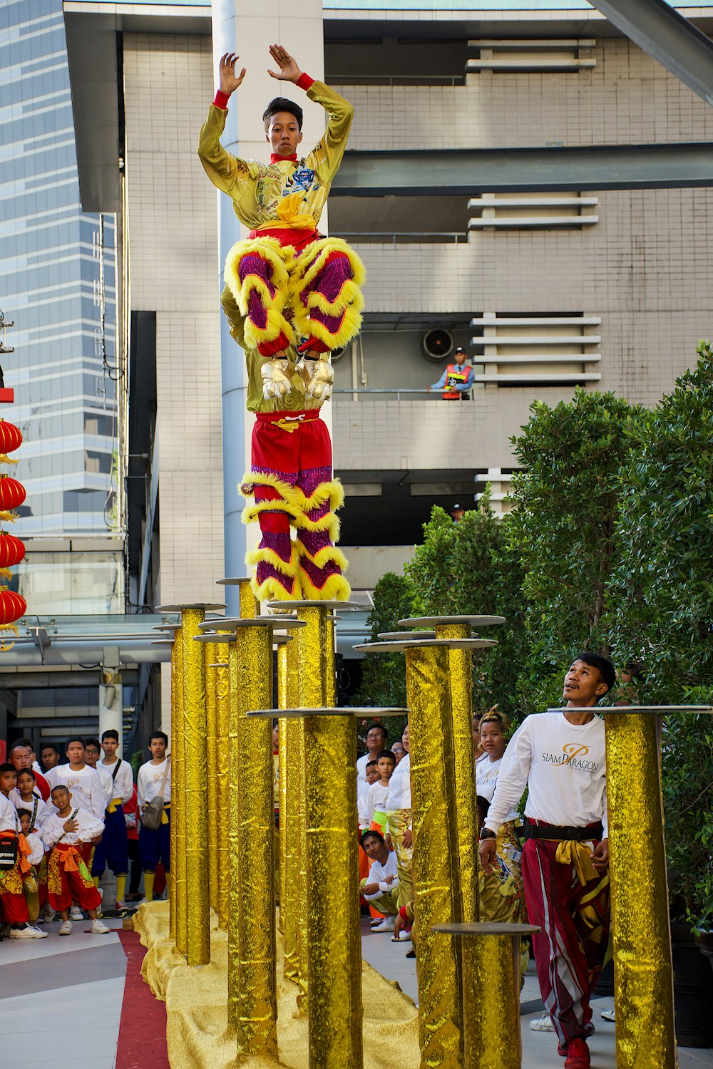 Hombre en camiseta blanca de cuello redondo de pie cerca de la estatua del dragón amarillo y rojo durante el día