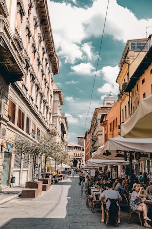 A cozy café terrace in a bustling European city, with colorful umbrellas and locals chatting.